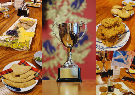 Scottish oatcakes displayed with tartan napkins, cheeses and flags. A trophy is in the middle of the image